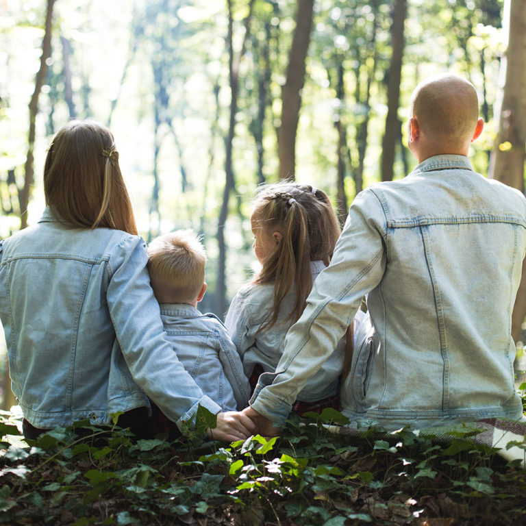 Familia sentada en un tronco en el bosque