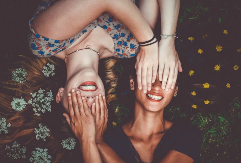 2 mujeres acostadas en un campo de flores sonriendo