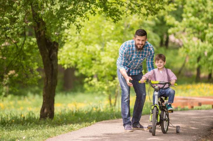 Padre enseñando a su hijo a andar en bici