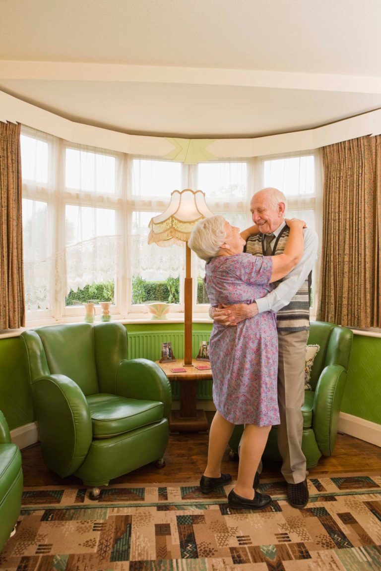 esposos ancianos bailando en la sala