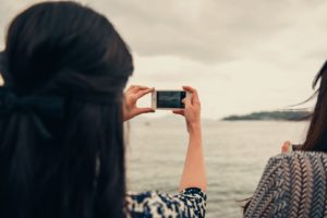 Mujer usando su celular para tomar una foto de un lago