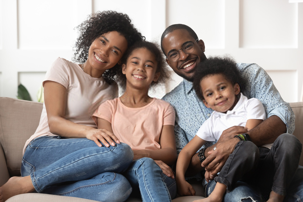 familia sonriendo en un sofa viendo a la camara