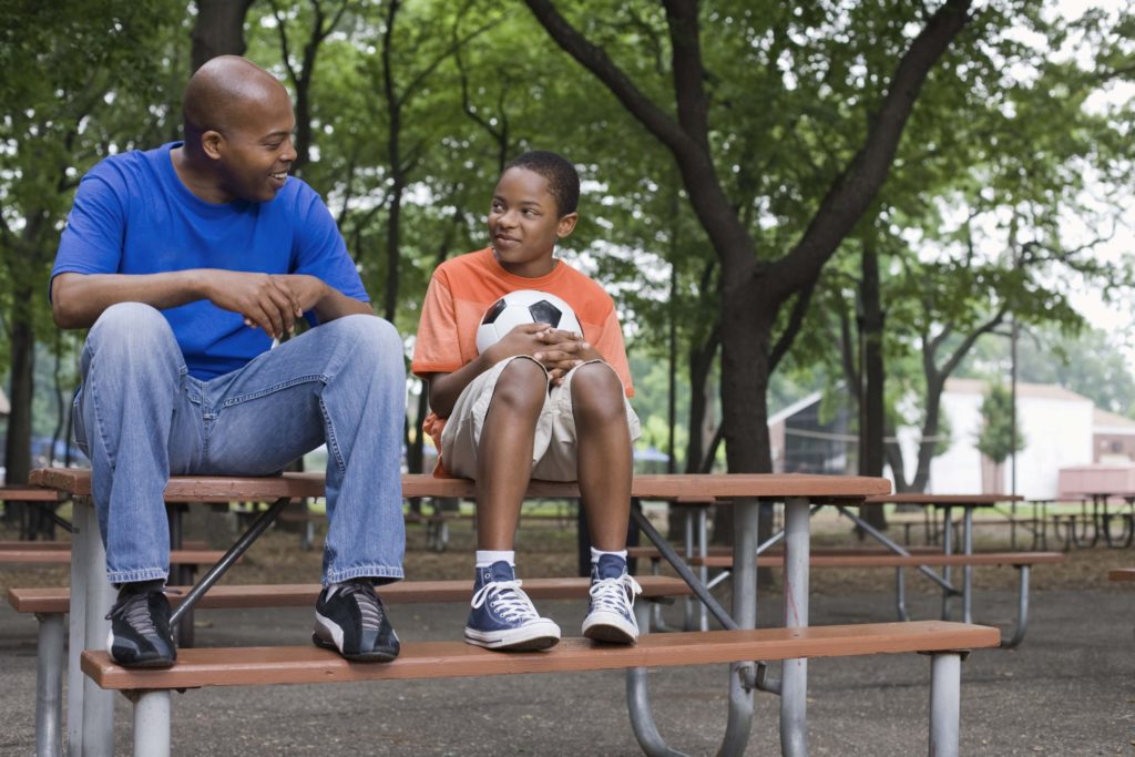 padre vacilando con su hijo en el parque