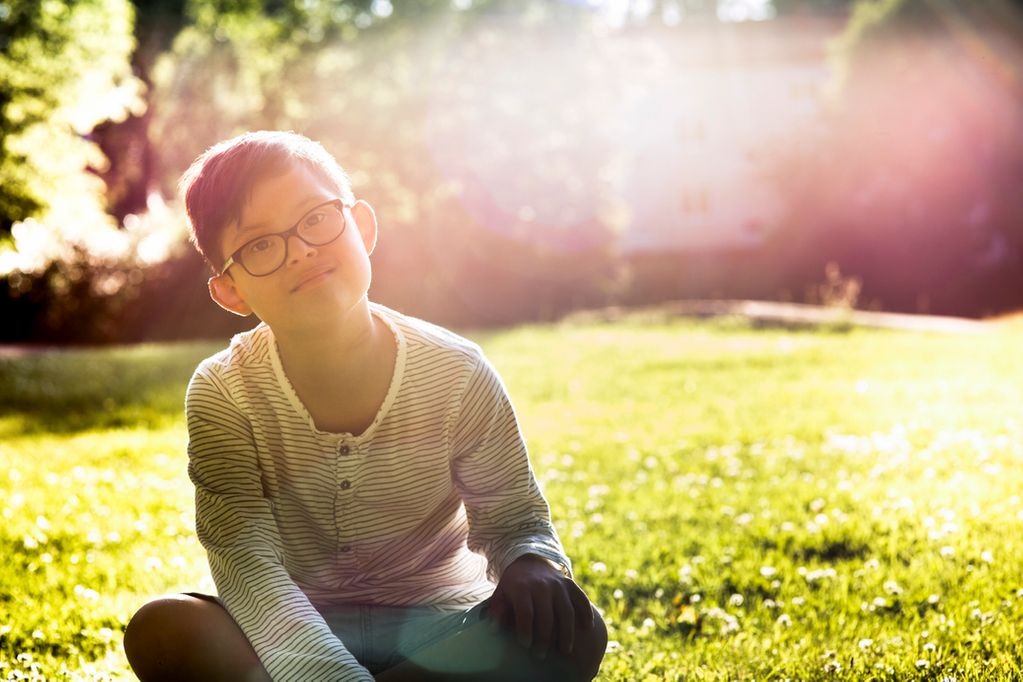 niño con sindrome de down sentado en el campo alegre