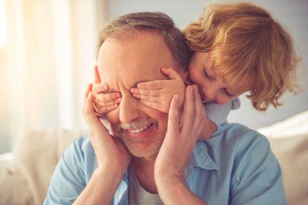 niño tapandole los ojos su abuelo que sonrie