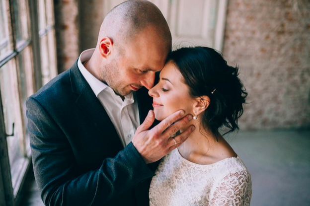 hombre vestido de novio besando a su nueva esposa