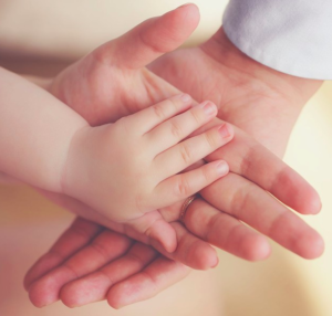 la mano de un bebe tocando a la mano de su madre y padre