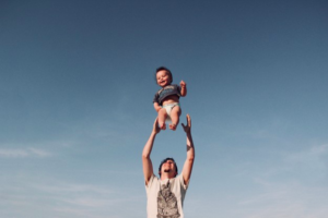 niño siendo alzado por su padre con una sonrisa en su rostro