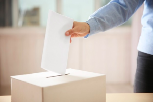 mujer metiendo un sobre en una caja de elecciones