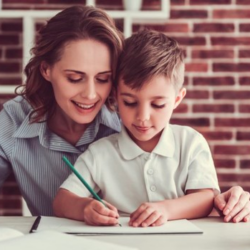 niño aprendiendo a escribir ayudado por su mamá