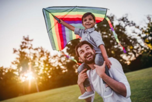 Niño jugando con una papalote junto a su padre