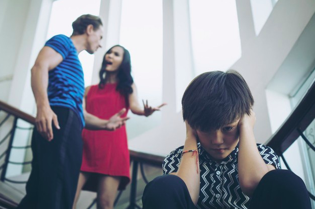 niño tapando sus orejas mientras sus padres se pelean