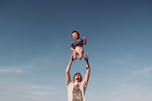 niño siendo alzado por los aires por su padre sonriendo