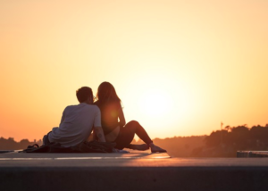 novios apoyados viendo un atardecer