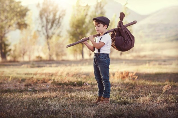 niño en el campo con su ropa en un palo de madera