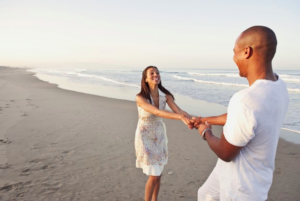 mujer tomada de las manos con su esposo en la playa