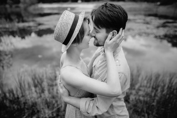 mujer y hombre apunto de besarse a la orilla de un lago