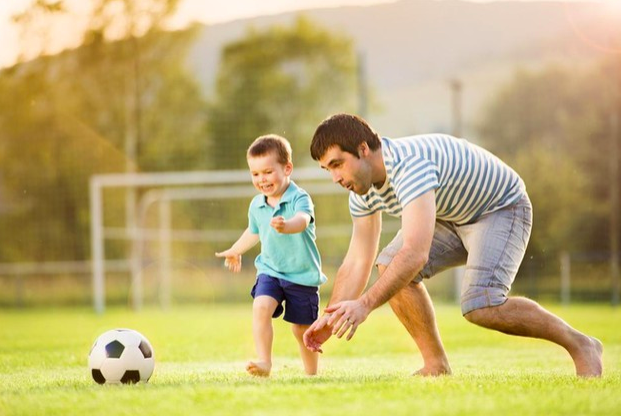 niño y padre jugando futbol