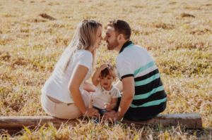 Padre y madre sentados en un tronco en el campo