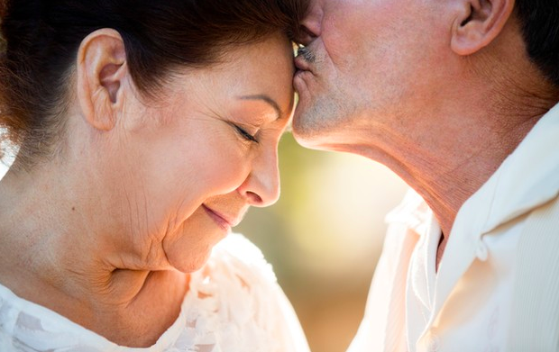 Esposo adulto mayor dando un beso en la frente a su esposa