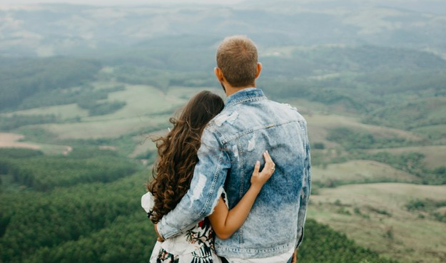 Hombre y mujer abrazados viendo unas montañas