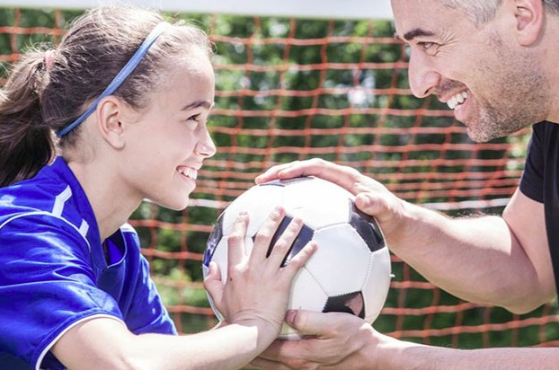 niña jugando futbol con su padre