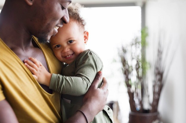 padre sonriendo con su hijo en brazos