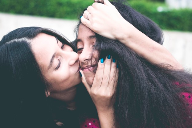 madre besando a su hija en la mejilla