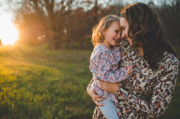 mamá alegre junto a su hija sonriendo en un atardecer