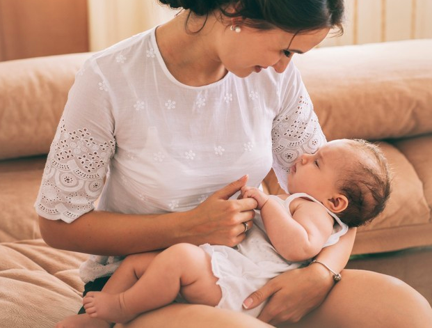 madre sentada en un sofa viendo a su bebe con ternura