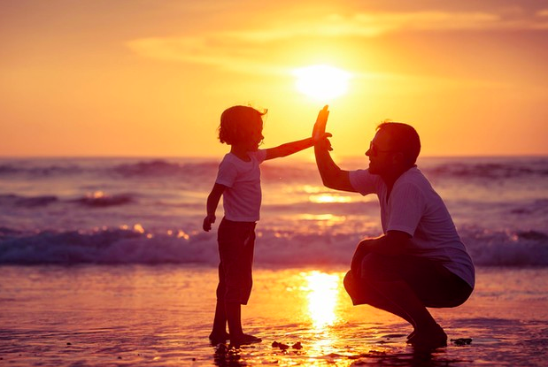 Niño dando los cinco a su padre en la playa