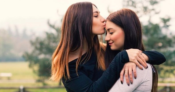 Mamá joven besando en la frente a su hija joven