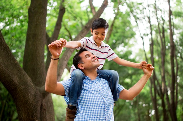 Papá con su hijo en los hombros en un parque