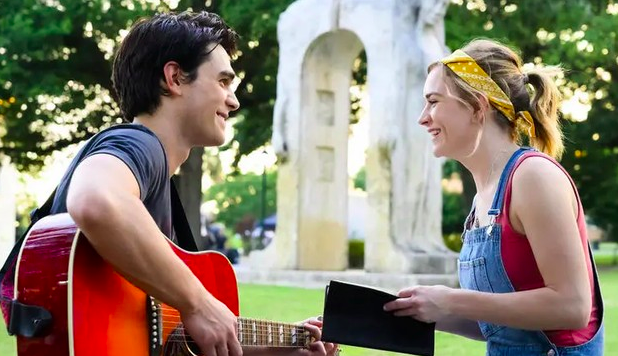 hombre con guitarra junto a mujer con una libreta