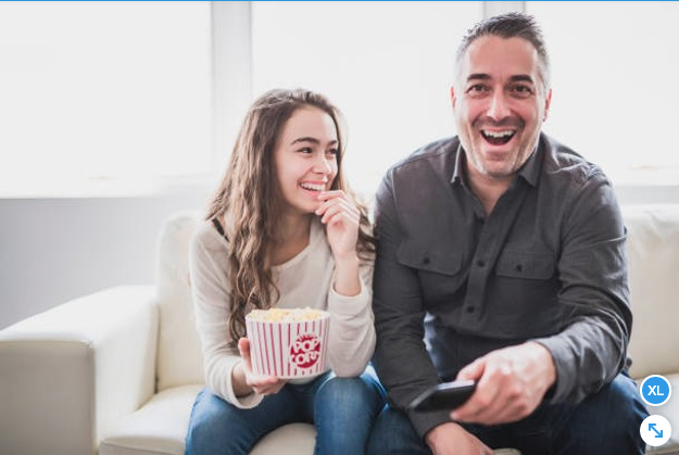 Padre y su hija viendo una pelicula con palomitas