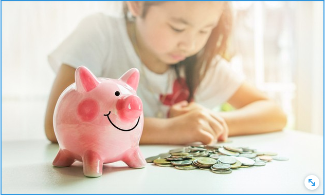 niña contando monedas junto a una alcancia