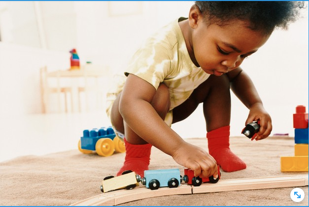 Niño pequeño jugando con un tren de madera