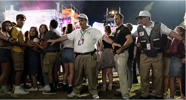 Hombres deteniendo una multitud que observa algo en un concierto
