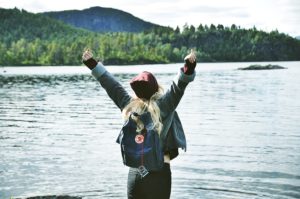 mujer con los brazos abiertos viendo un lago