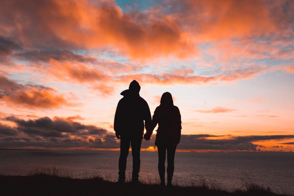 Mujer y hombre tomandose de las manos viendo hacia el horizonte
