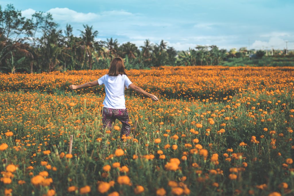 mujer caminando por un campo de flores