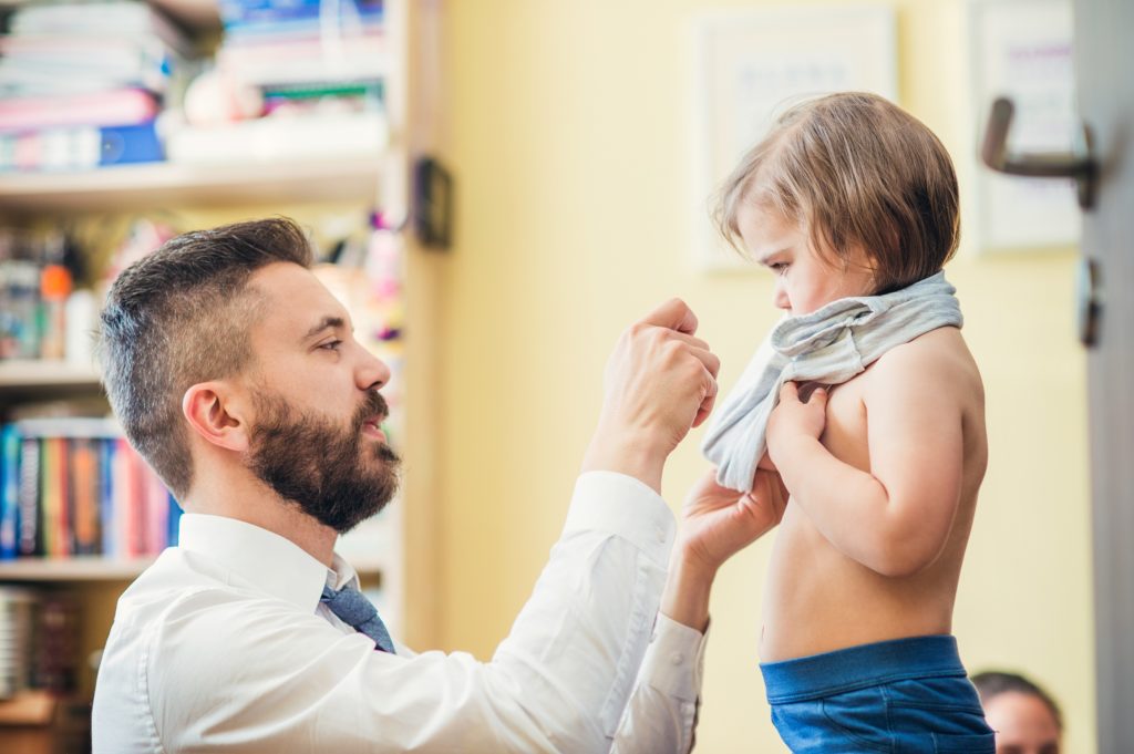 niño aprendiendo a vestirse junto a su padre