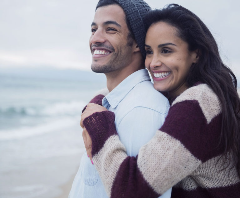 Mujer y hombre abrazados viendo el mar