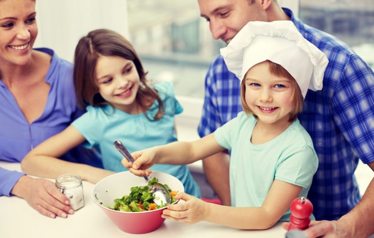 2 niñas preparando una ensalada con sus papá y mamá