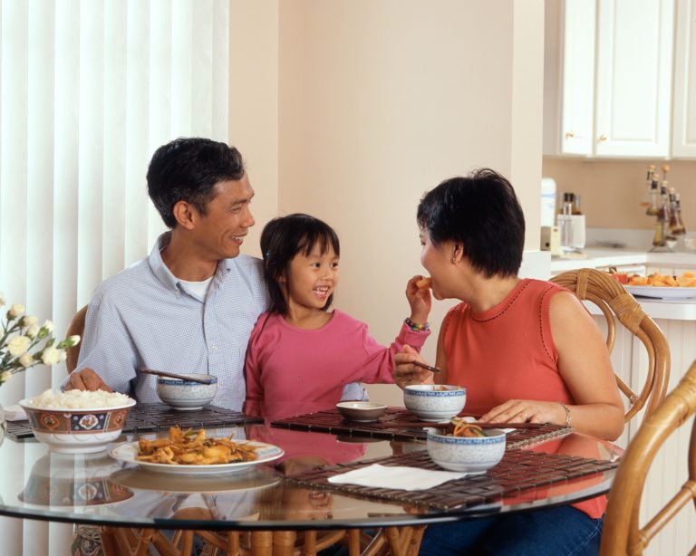 niña comiendo junto a su madre y padre