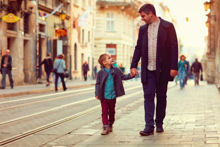 Hijo y padre caminando por un acera