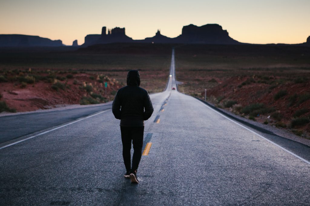 hombre caminando por una carretera en el desierto
