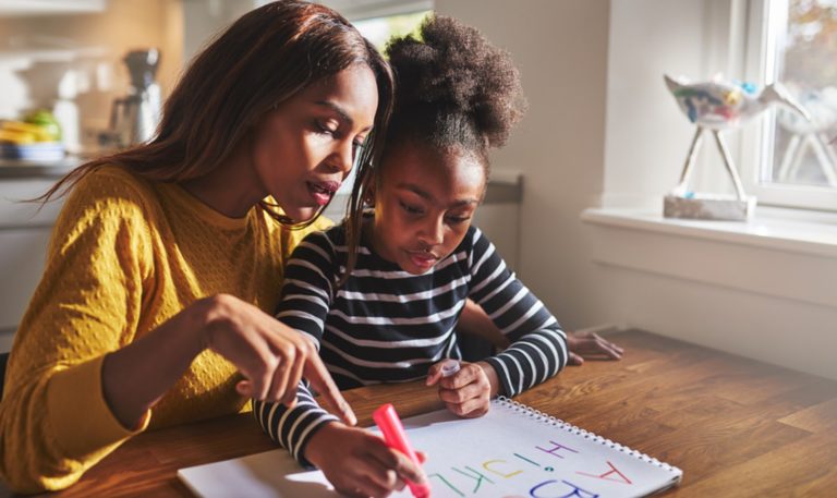 Mujer ayudando a su hija a aprender a escribir