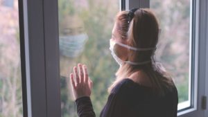 Mujer con mascarilla viendo la ventana