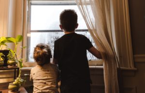 Niño y niña viendo la nieve por la ventana